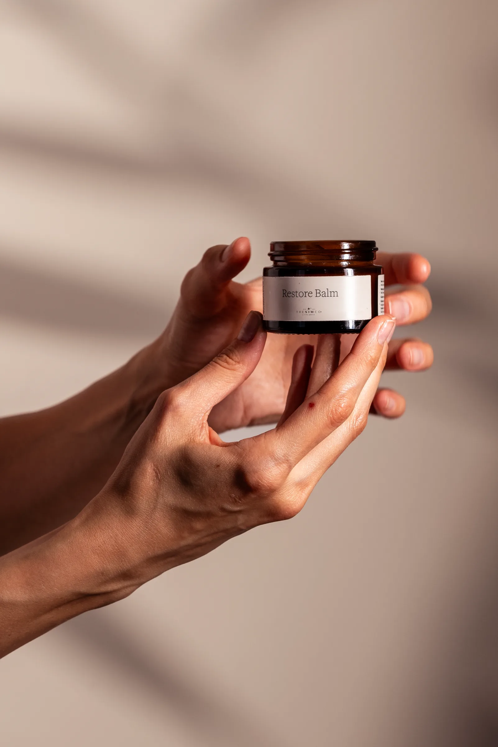Restore Balm — el üstünde amber kavanoz